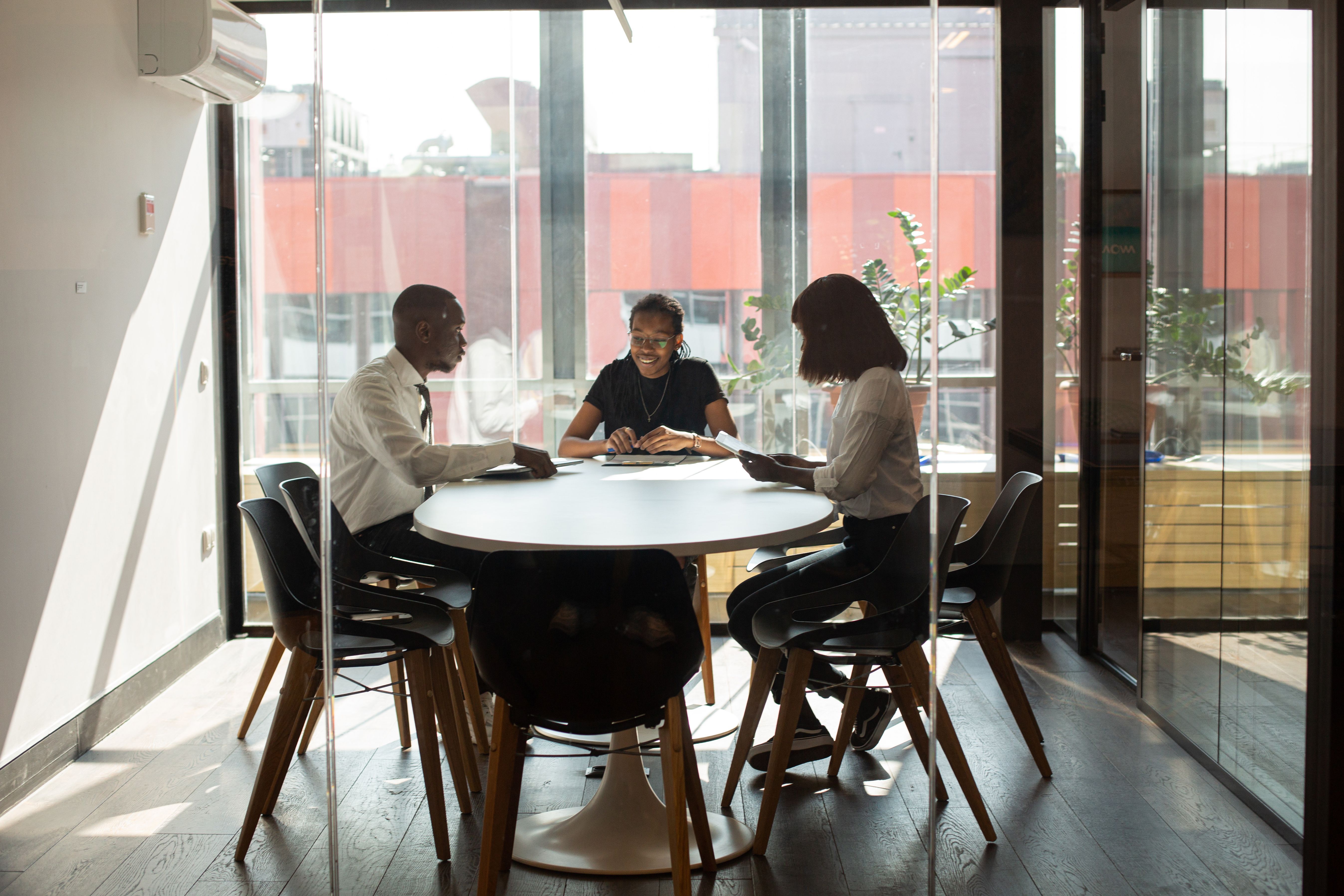 A small executive group meeting in a glass-walled boardroom.