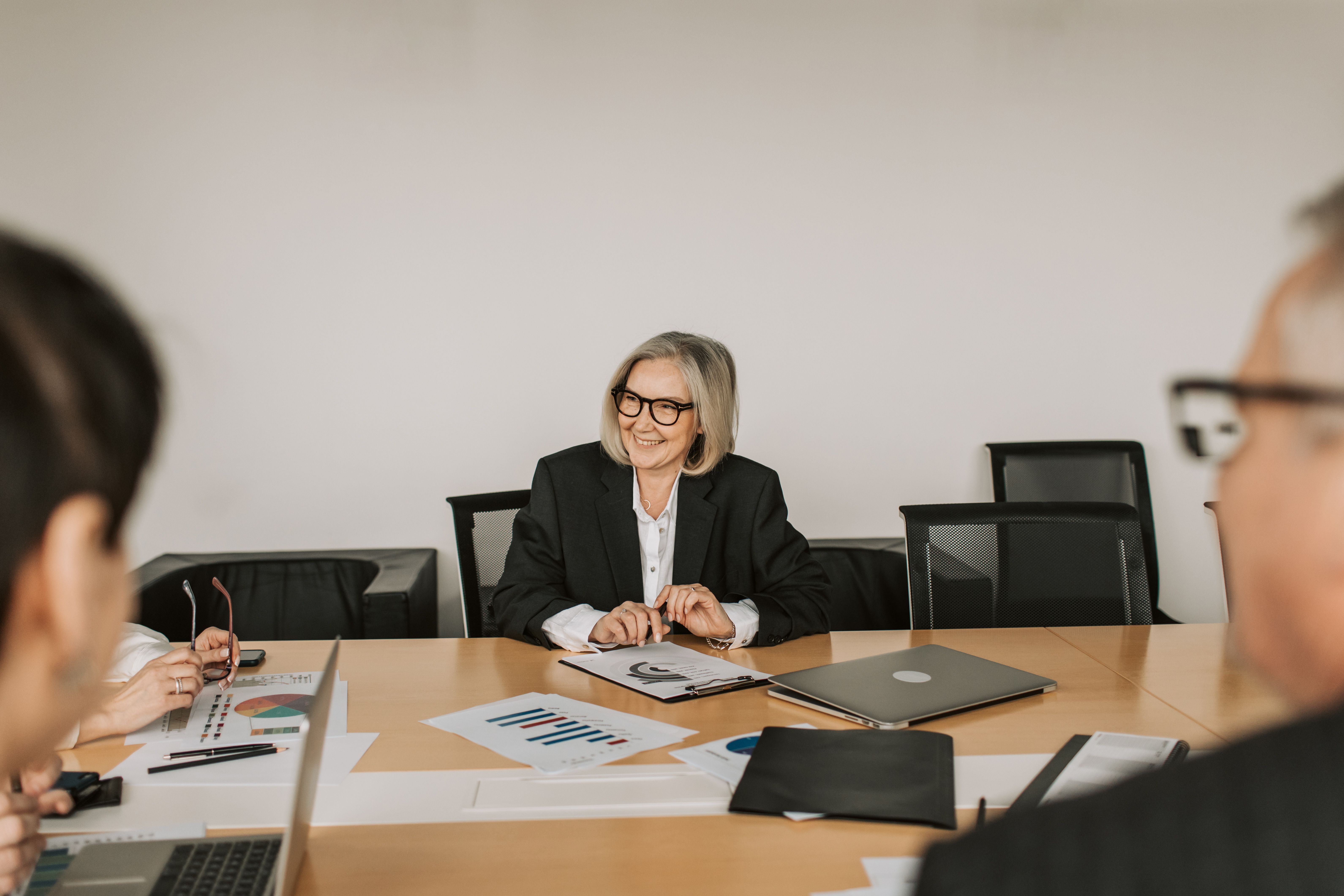 A senior leader presenting to colleagues across a boardroom table.