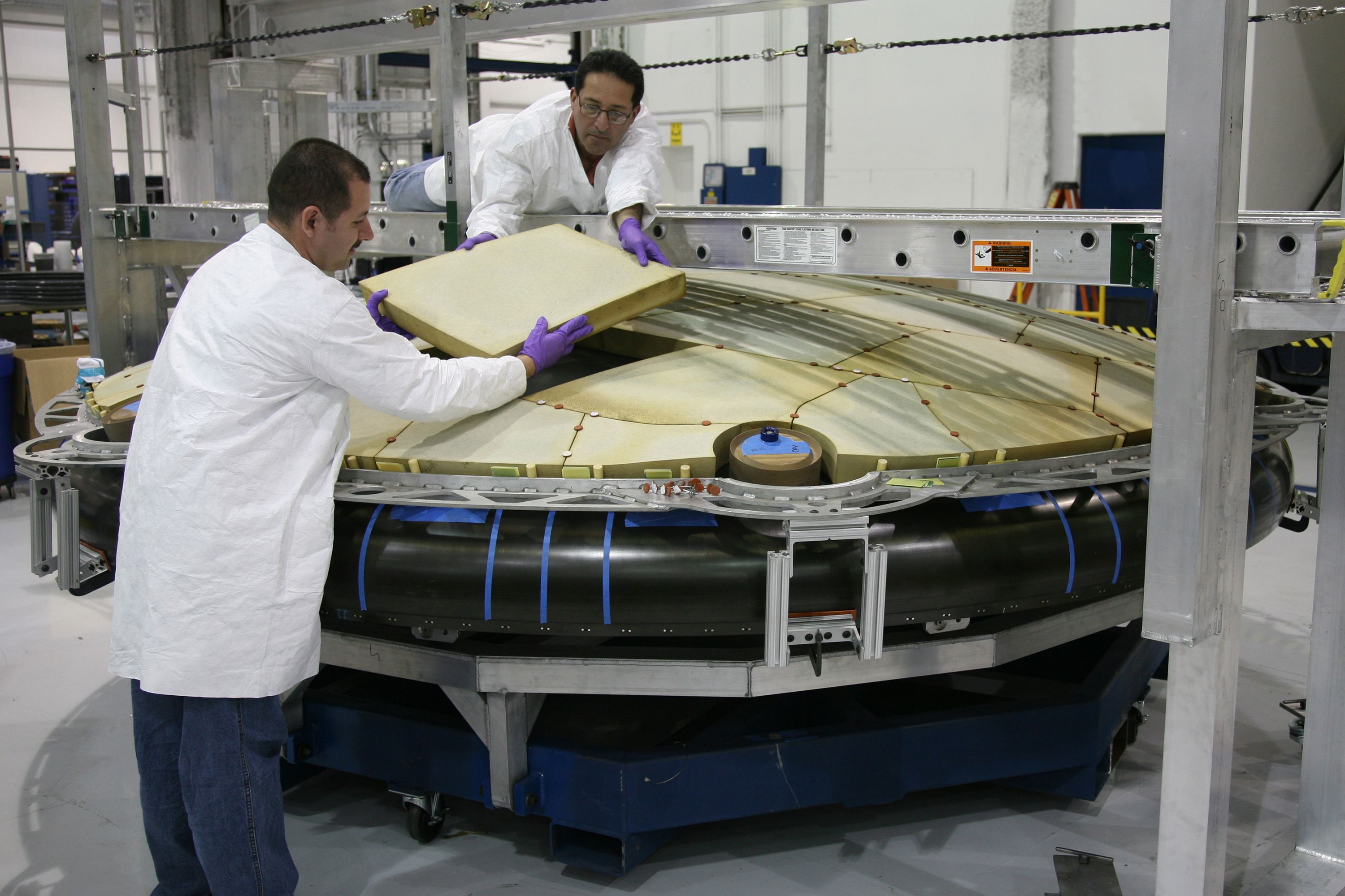 Technicians handling a large component in a clean production environment.
