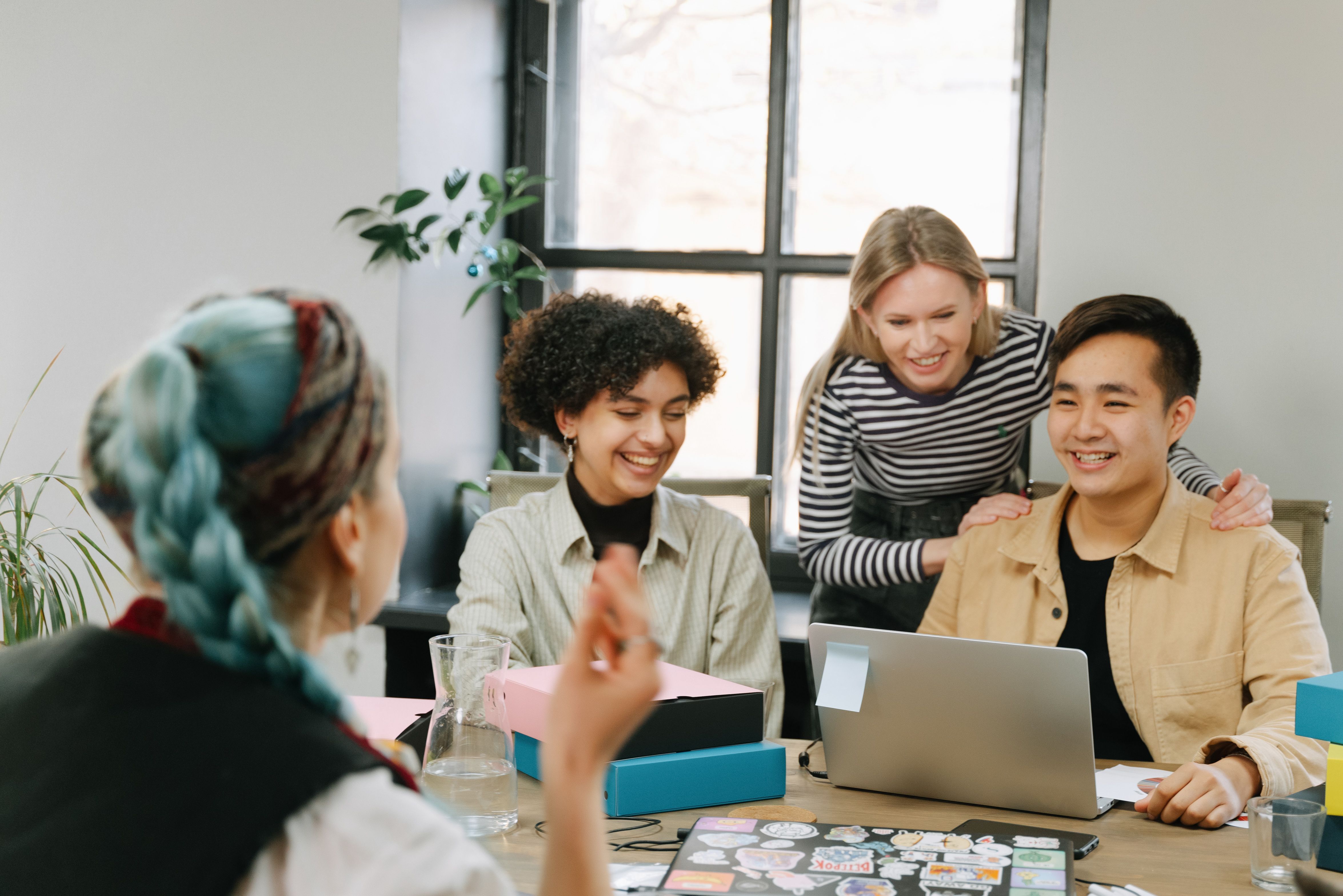 A team in animated discussion around a laptop.